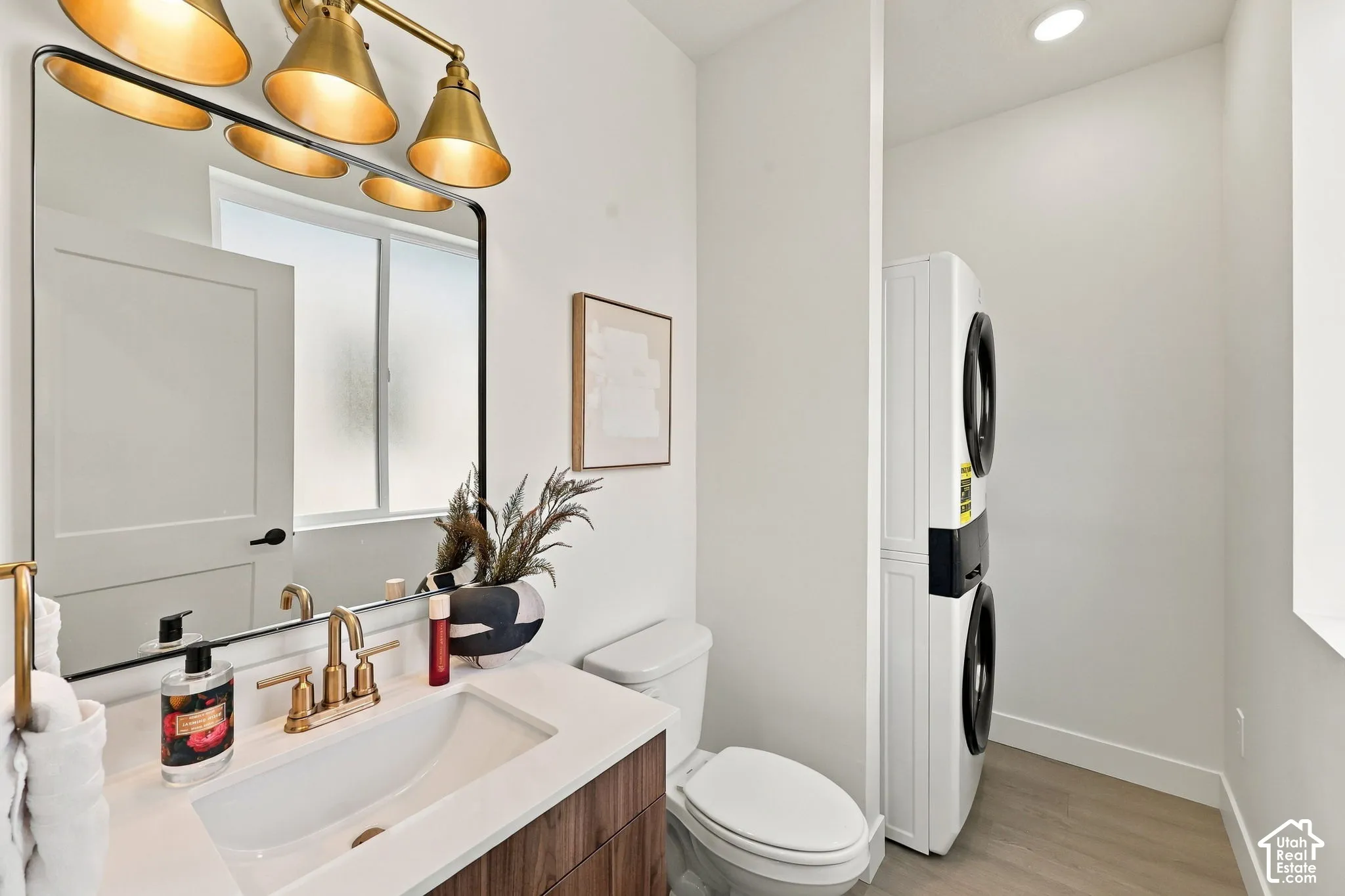 Vanity with white countertop and integrated sink, gold-finish faucet, and coordinating overhead lighting