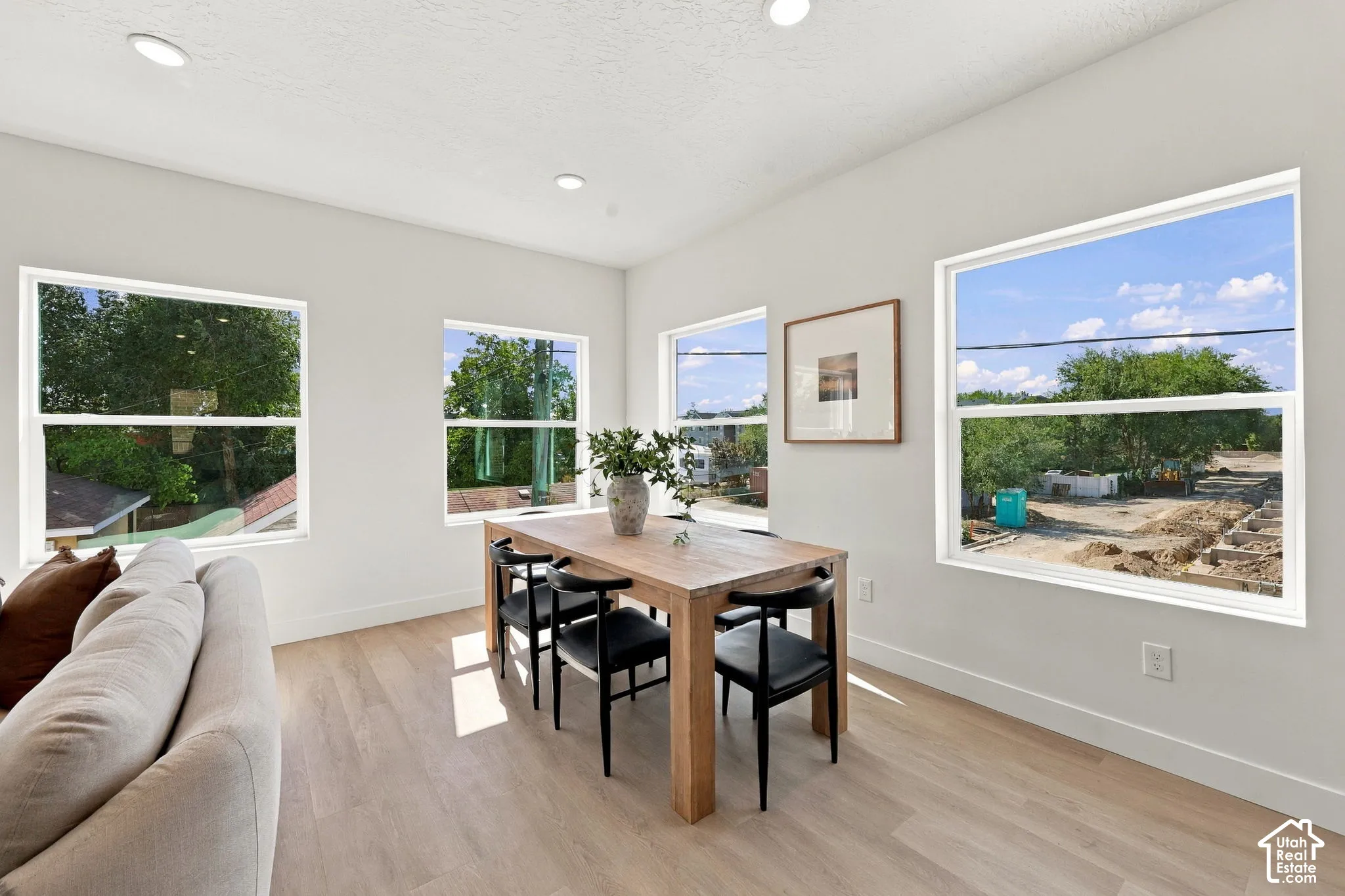 Recessed lighting, light wood-finish flooring, and multiple windows providing ambient light