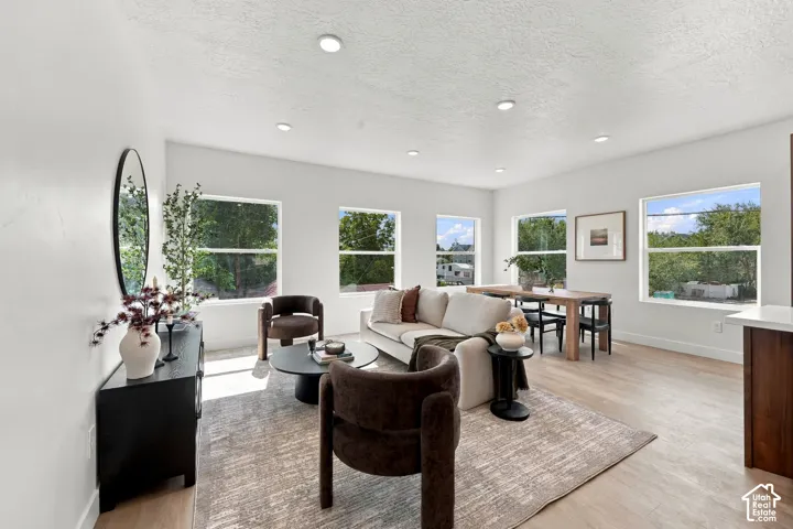 Recessed lighting, light wood-finish flooring, multiple large windows, and a built-in wood-tone cabinet with a light-tone countertop
