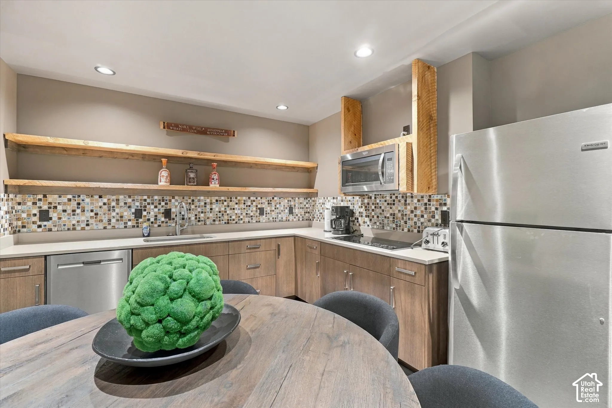 Kitchenette featuring light wood-finish cabinetry, stainless steel appliances, mosaic tile backsplash, and open wood shelving
