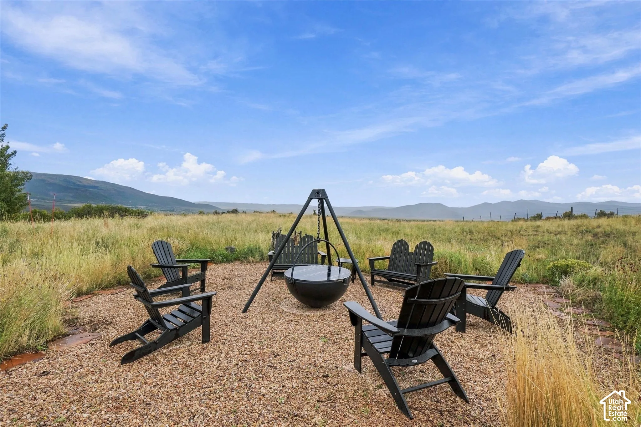 Gravel patio area featuring a built-in fire pit, surrounded by open fields and distant mountains