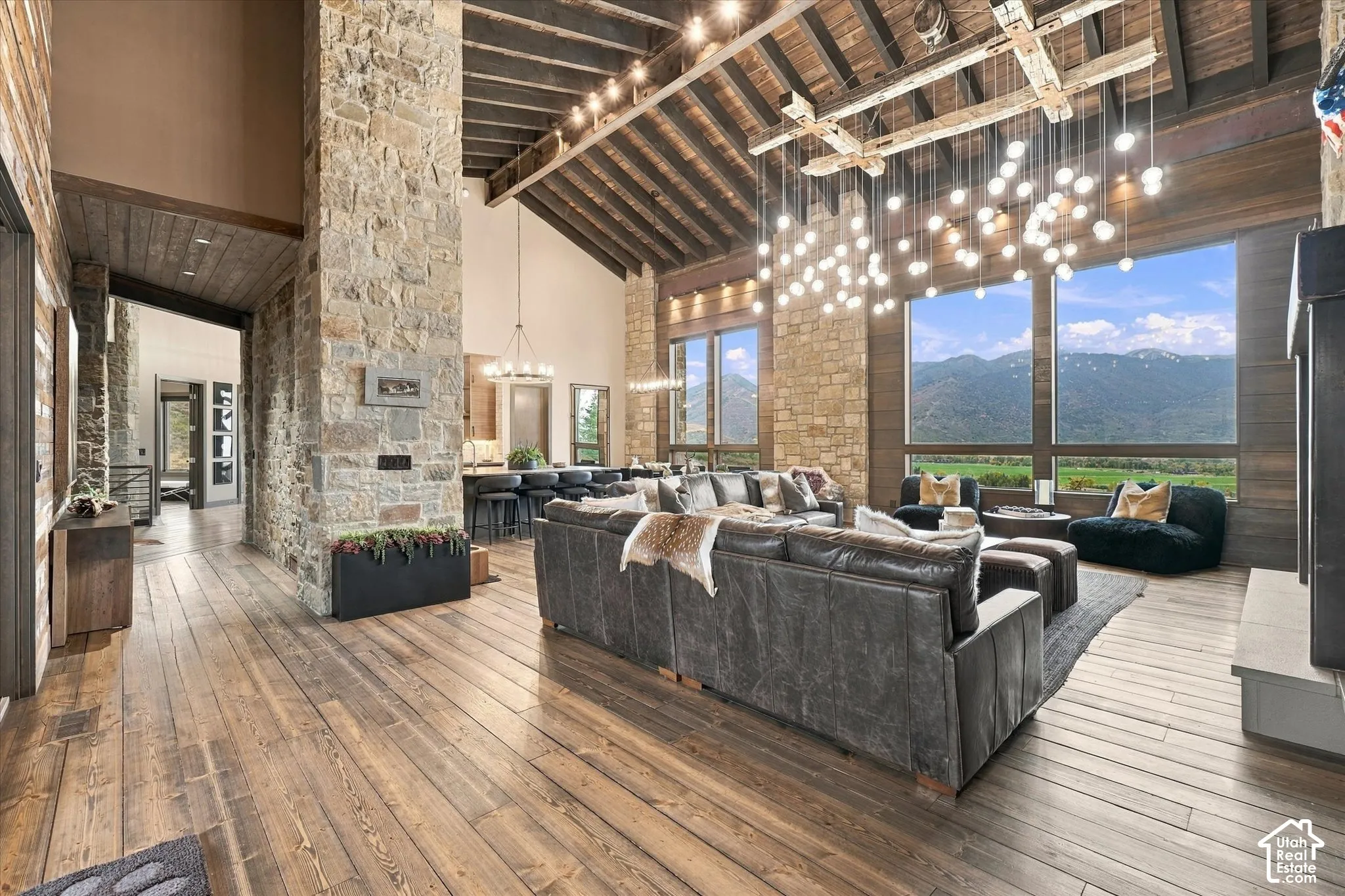 Vaulted wood-paneled ceiling, exposed wood beams, stone accent walls, expansive windows, and wood-finish flooring