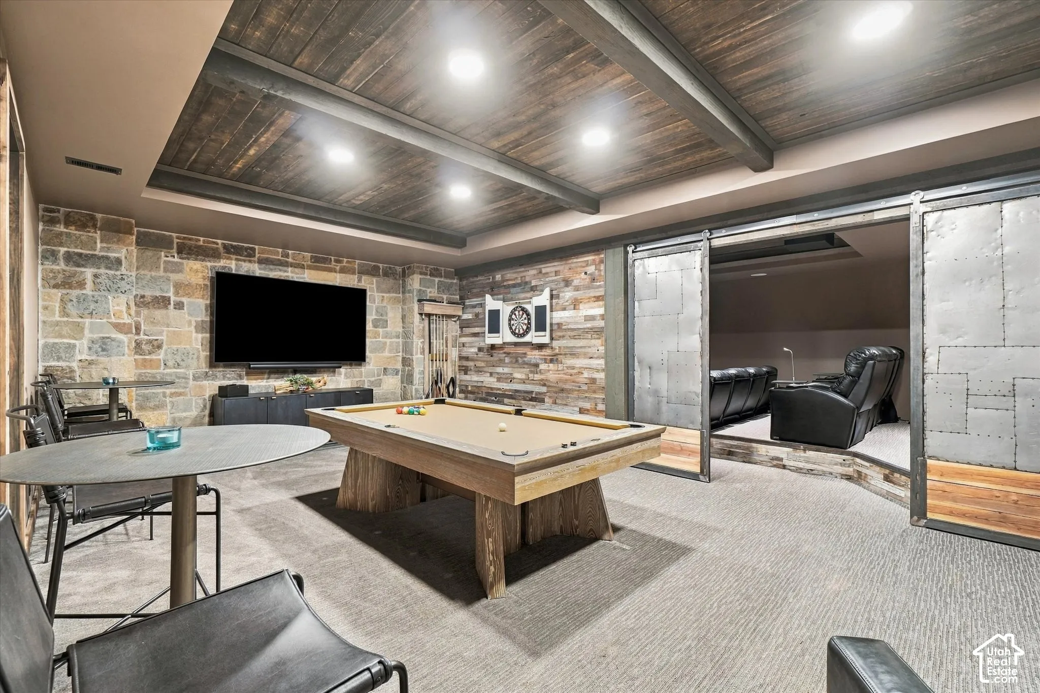 Stone accent wall, wood-finish plank ceiling, recessed lighting, carpeted flooring, and barn-style sliding metal doors