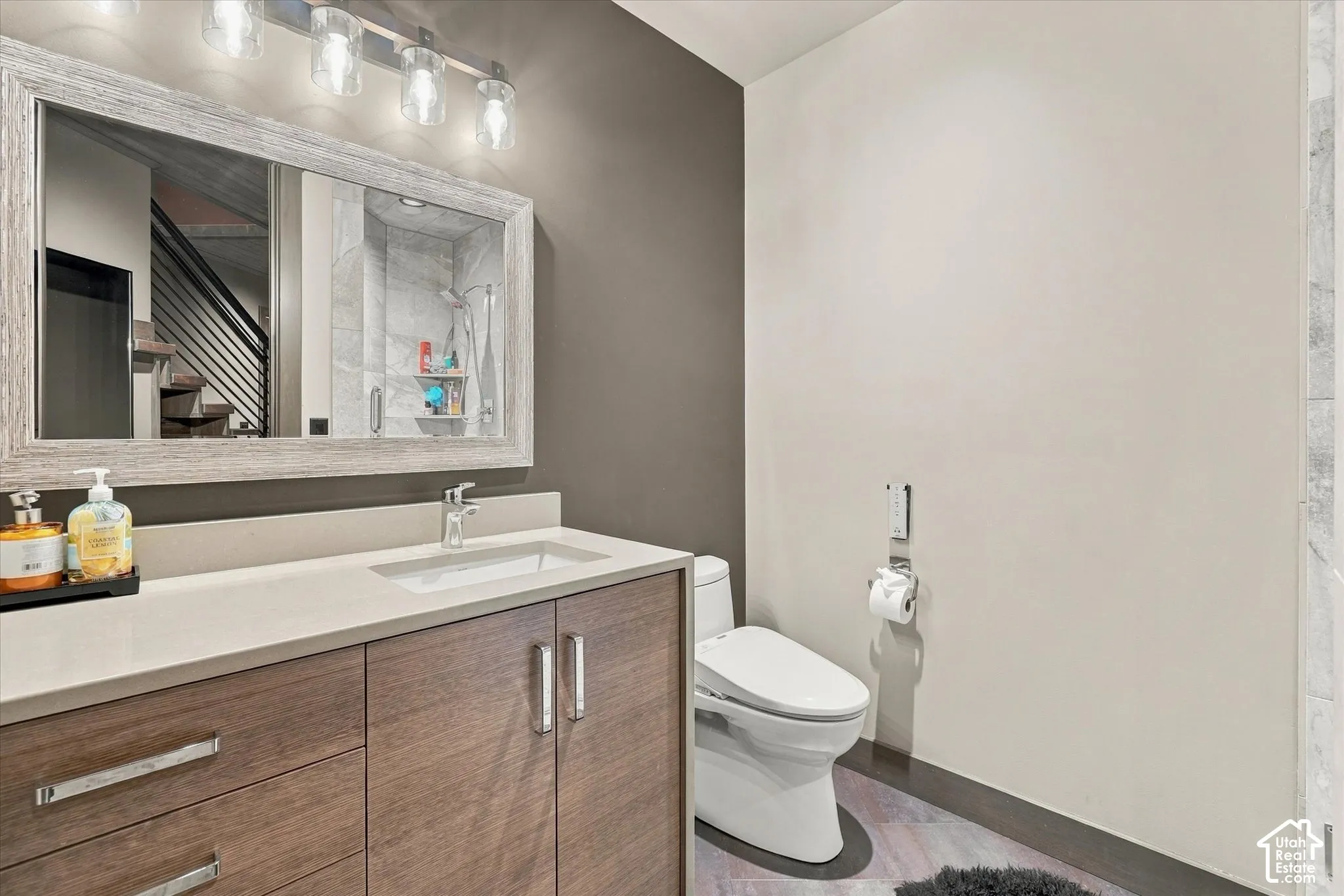 Wood-finish vanity with an integrated sink, light-toned countertop, and framed mirror