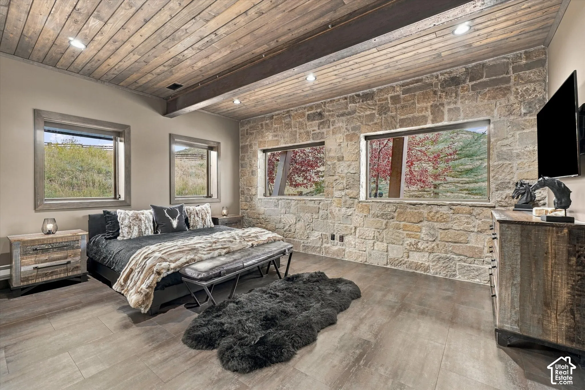 Wood-finish plank flooring, wood-clad ceiling, stone accent wall, recessed lighting, and built-in windows