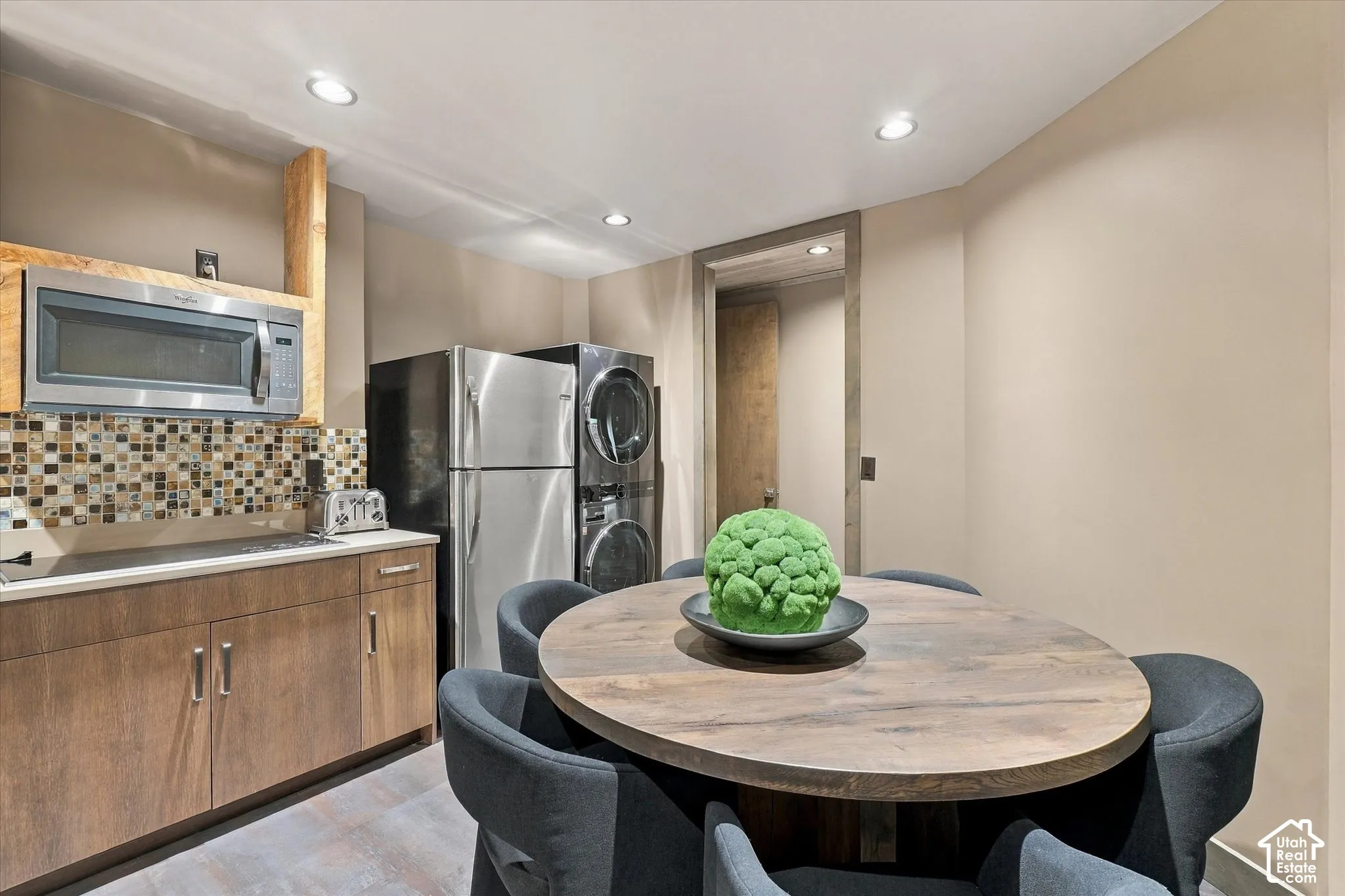 Compact kitchen area featuring stainless steel appliances, mosaic tile backsplash, wood-finish cabinetry, and recessed lighting