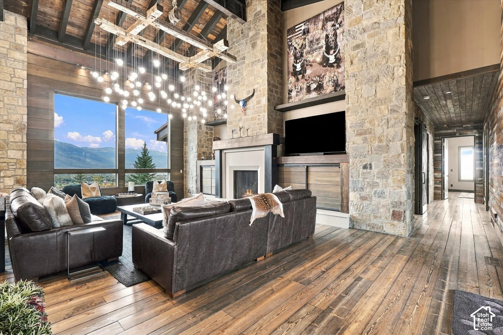 Spacious living area featuring stone accent walls, wood-finish flooring, and a vaulted wood-beam ceiling