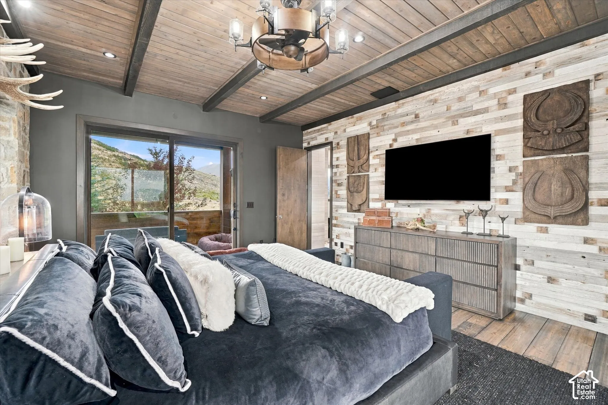 Wood-paneled vaulted ceiling with exposed beams, wood-finish flooring, full-wall horizontal wood paneling, sliding glass door, and a built-in light fixture