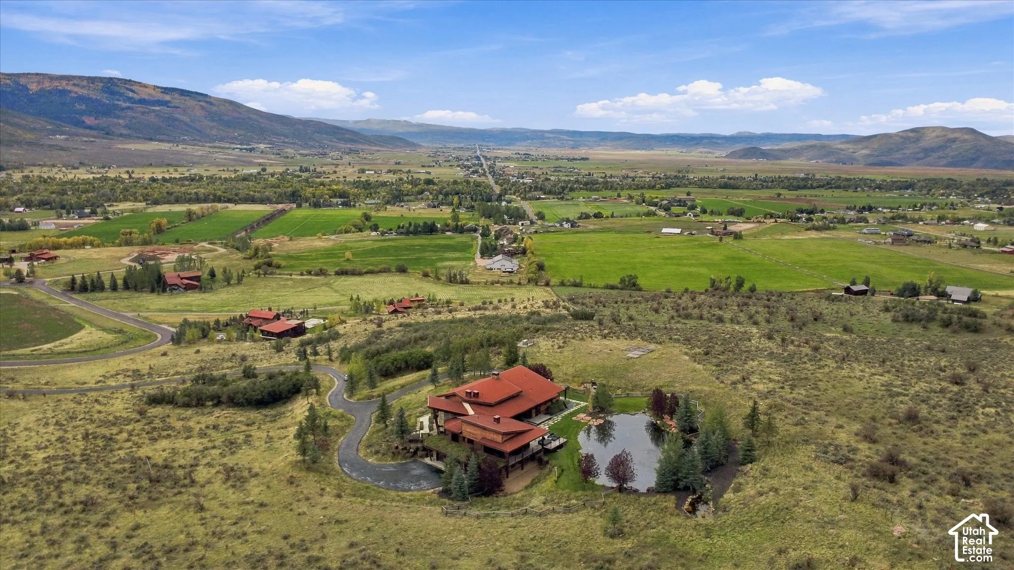 Extensive acreage with a private pond, mountainous backdrop, and winding driveway