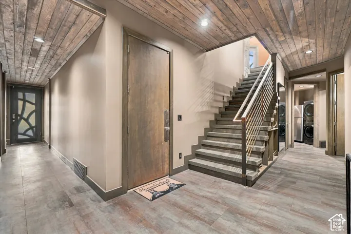 Wood-finish flooring throughout, featuring a staircase with metal railings and a built-in laundry area