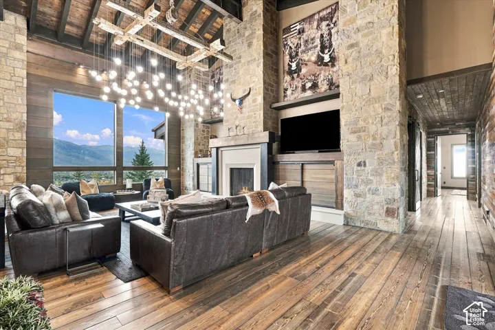Spacious living area featuring stone accent walls, wood-finish flooring, and a vaulted wood-beam ceiling