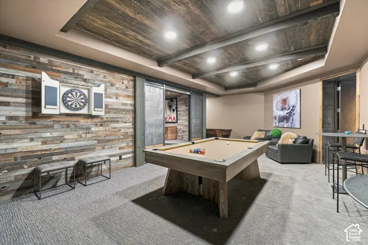 Reclaimed wood accent wall, wood-paneled ceiling with recessed lighting, gray patterned carpeting, and industrial-style sliding barn doors