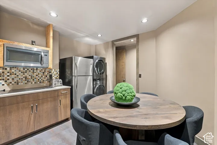 Compact kitchen area featuring stainless steel appliances, mosaic tile backsplash, wood-finish cabinetry, and recessed lighting