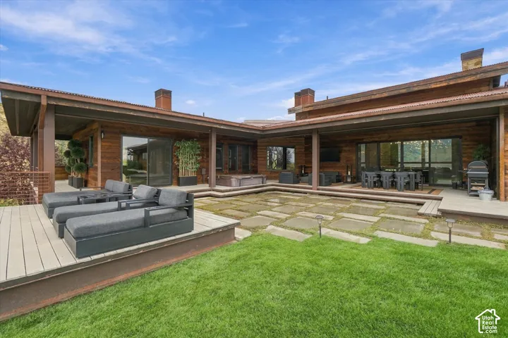 Expansive covered patio with wood-finish siding, multiple access points, and a stone paver patio