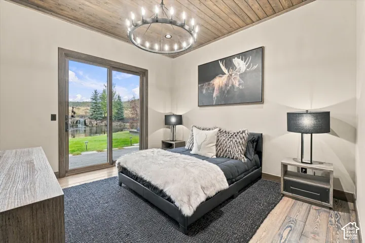 Hardwood flooring, wood-paneled ceiling, sliding glass door, recessed lighting, and chandelier
