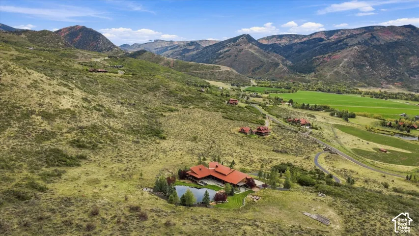Expansive property featuring a red-roofed residence, a private pond, and surrounding hillsides