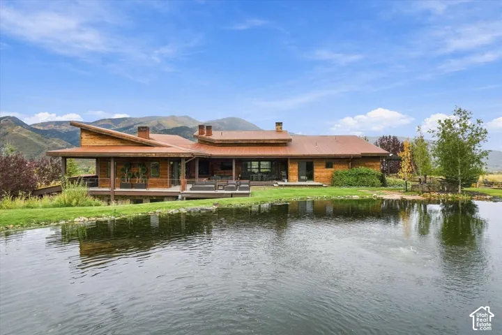 Wood-sided residence with multiple outdoor deck areas, a private pond, and mountain background