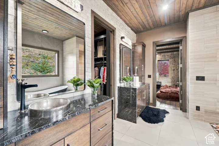 Black marbled countertop with an oval vessel sink, wood-finish vanity, and a black framed mirror