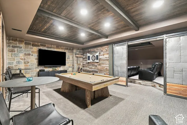 Stone accent wall, wood-finish plank ceiling, recessed lighting, carpeted flooring, and barn-style sliding metal doors