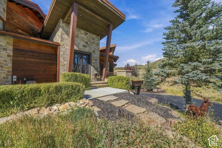 Stone exterior with wood-finish garage door, custom double entry doors, wood soffits, and a natural stone walkway