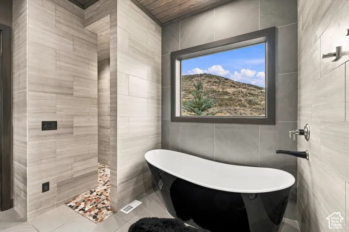 Freestanding black and white soaking tub, wall-mounted tub filler, and a large window with natural scenery
