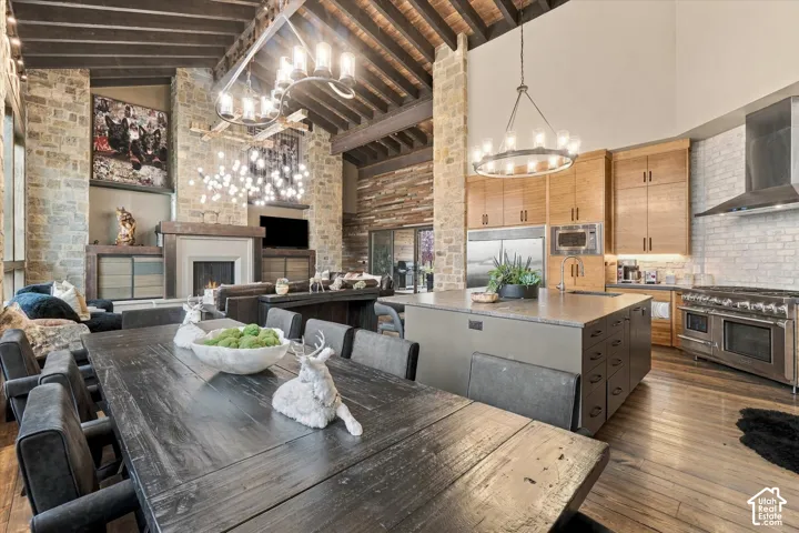 Vaulted exposed beam ceiling, stone accent walls, integrated fireplace, expansive kitchen island, and stainless steel appliances