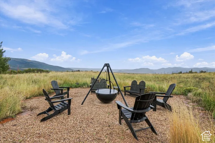Gravel patio area featuring a built-in fire pit, surrounded by open fields and distant mountains