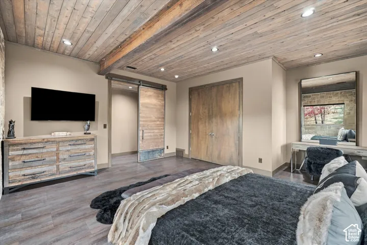 Wood-finish flooring with a wood-plank ceiling, exposed wood beam, and recessed lighting