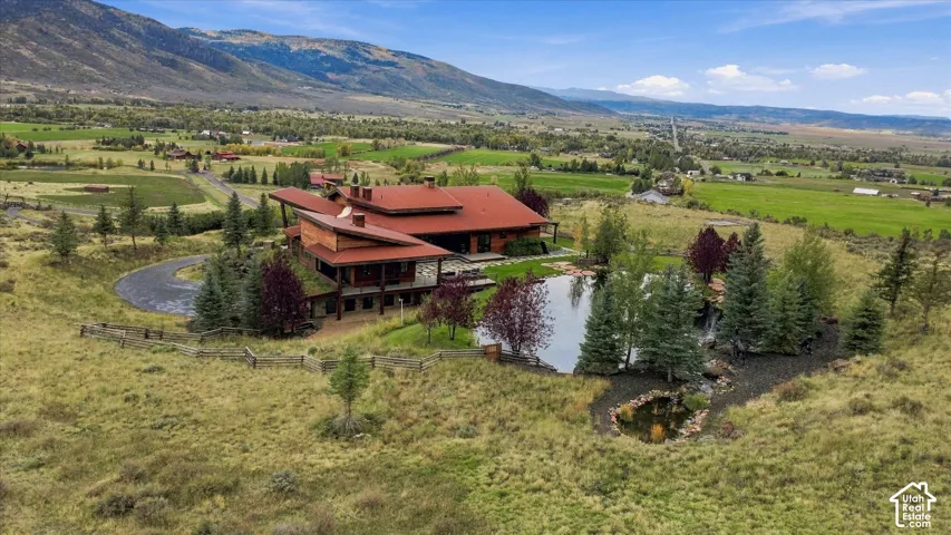 Expansive property featuring a multi-level residence with a red tile roof, two distinct ponds, mature landscaping, and a mountainous backdrop