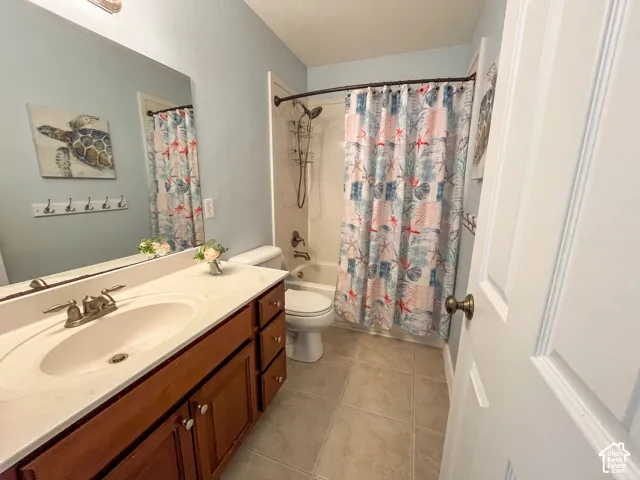 Full vanity mirror, integrated sink, wood-finish cabinetry, tile flooring, and a shower-tub combination