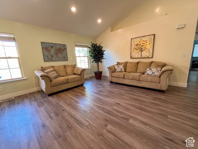 Vaulted ceiling with recessed lighting, multiple windows, and wood-finish flooring