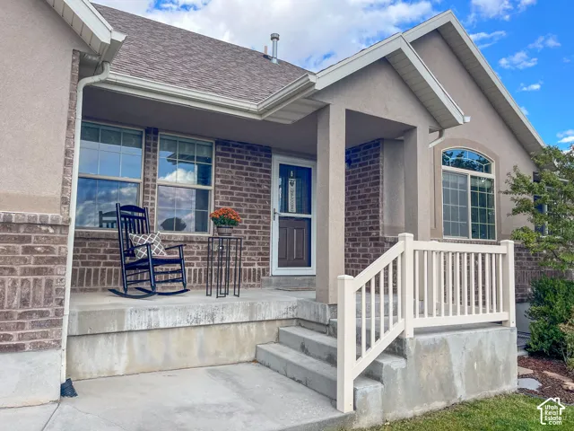 Covered entry porch featuring brick and stucco siding