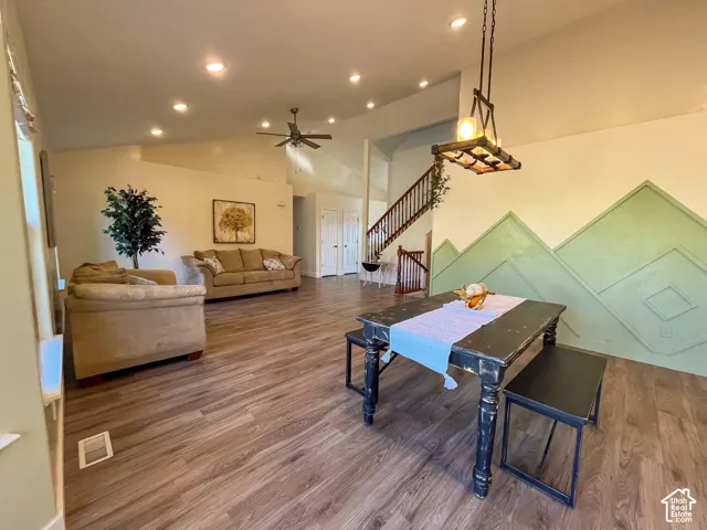 Wood-finish flooring, vaulted ceilings with recessed lighting, and a prominent staircase with dark wood railing