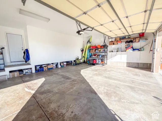 Spacious garage with an automatic overhead door, concrete flooring, and an interior access door