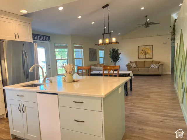 Kitchen island with integrated sink, vaulted ceiling, recessed lighting, wood-finish flooring, and ceiling fan