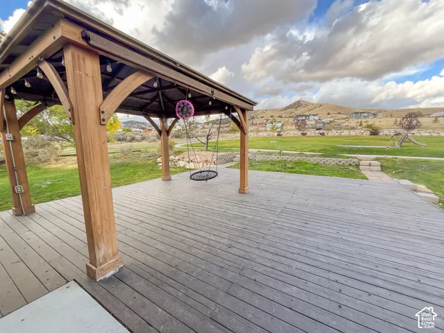 Expansive outdoor decking with a wood-finish gazebo, set against a backdrop of distant hills