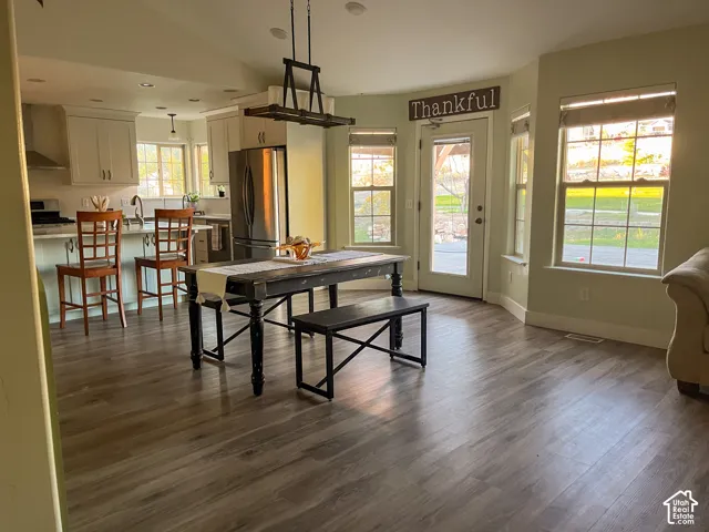Spacious open-concept area featuring wood-finish flooring, white cabinetry, recessed lighting, and stainless steel appliances