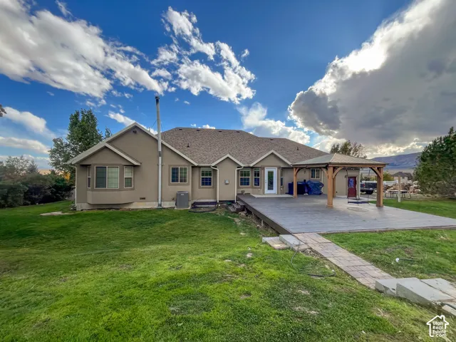 Spacious backyard featuring a large outdoor deck with a covered pergola, a bay window, and a pathway