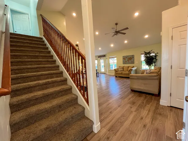 Wood-finish flooring throughout the open-concept living area, featuring recessed lighting and a ceiling fan