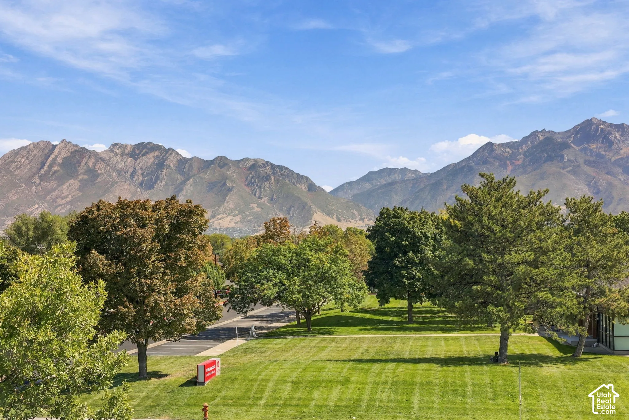 Expansive green space with mature trees and a clear mountain backdrop