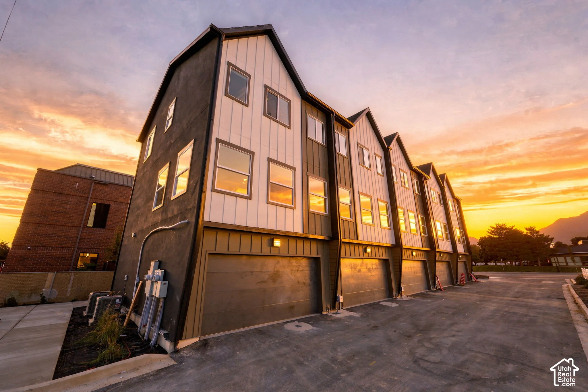 Modern multi-level townhome featuring a board and batten facade, attached garage doors, and multiple windows