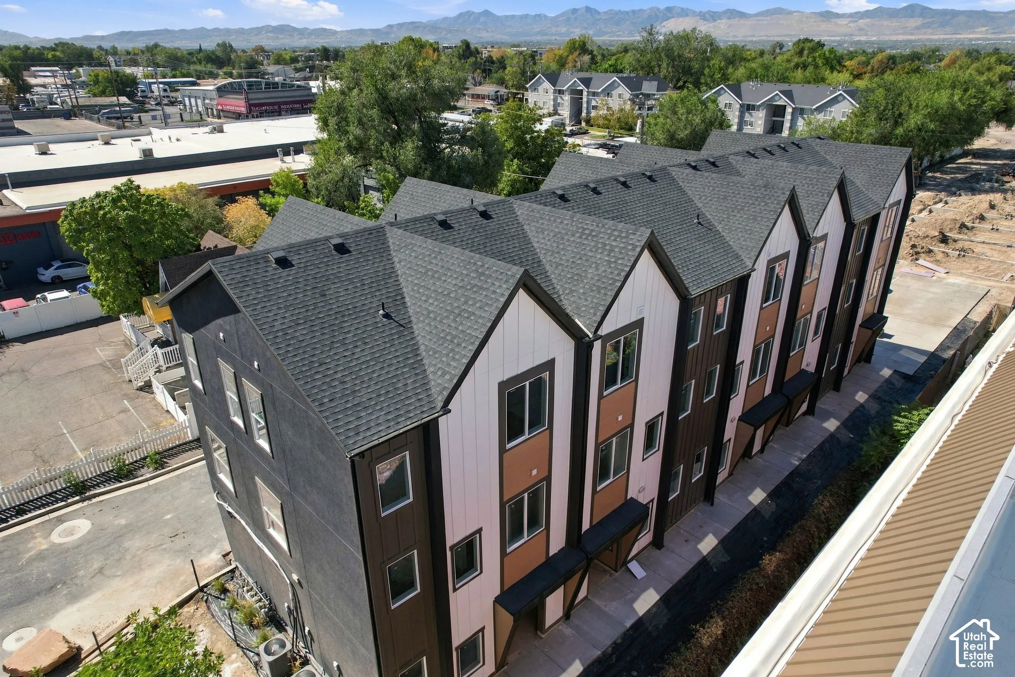 Modern townhome exteriors featuring multiple gables and a combination of dark siding, white paneling, and brown accents