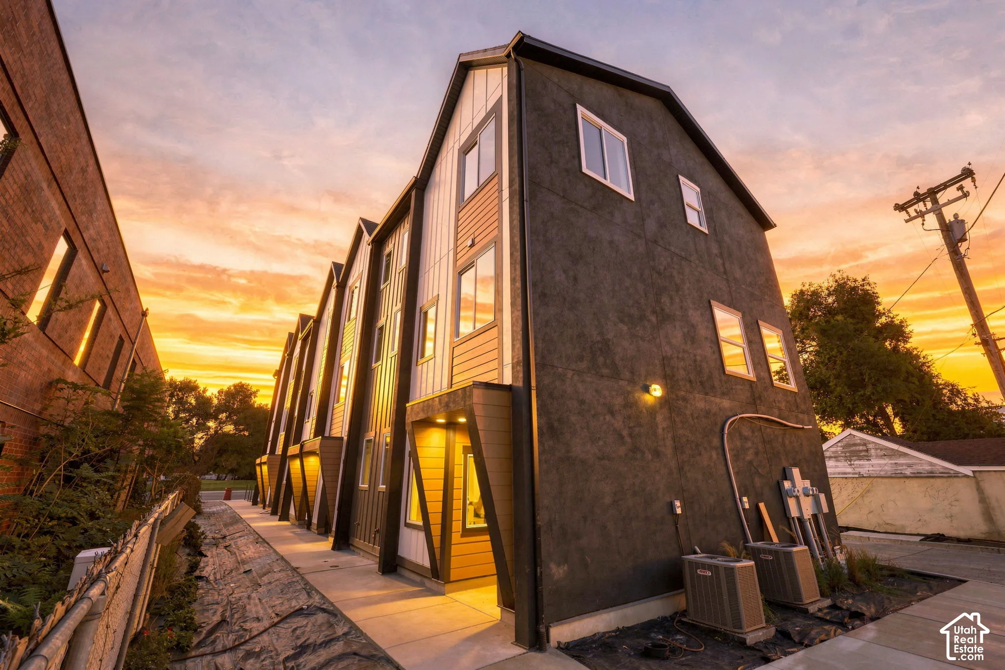 Modern multi-level townhome architecture with a contrasting dark stucco facade and light-toned siding accents