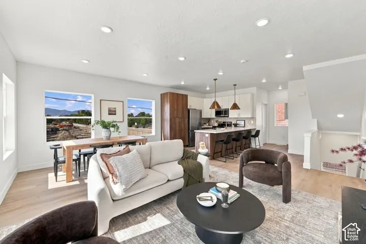 Open-concept living area with wood-finish flooring, recessed lighting, and large windows