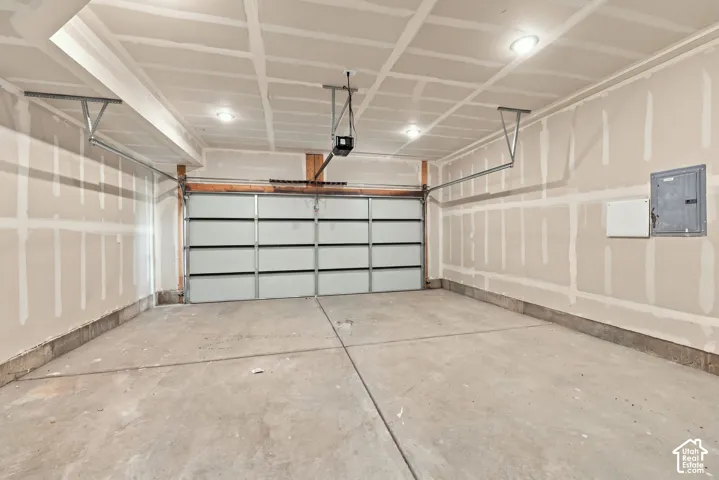 Spacious garage with exposed drywall, concrete flooring, and a segmented garage door