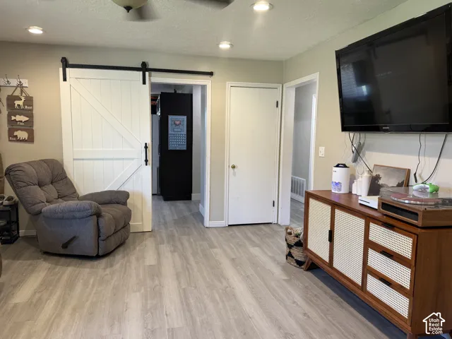 Wood-finish flooring throughout, featuring a white barn door with black hardware, and recessed lighting