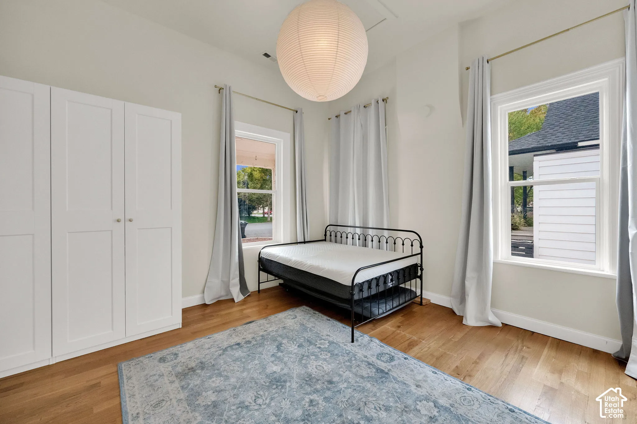Hardwood flooring, two windows with white trim, built-in white cabinetry, and a circular pendant light fixture