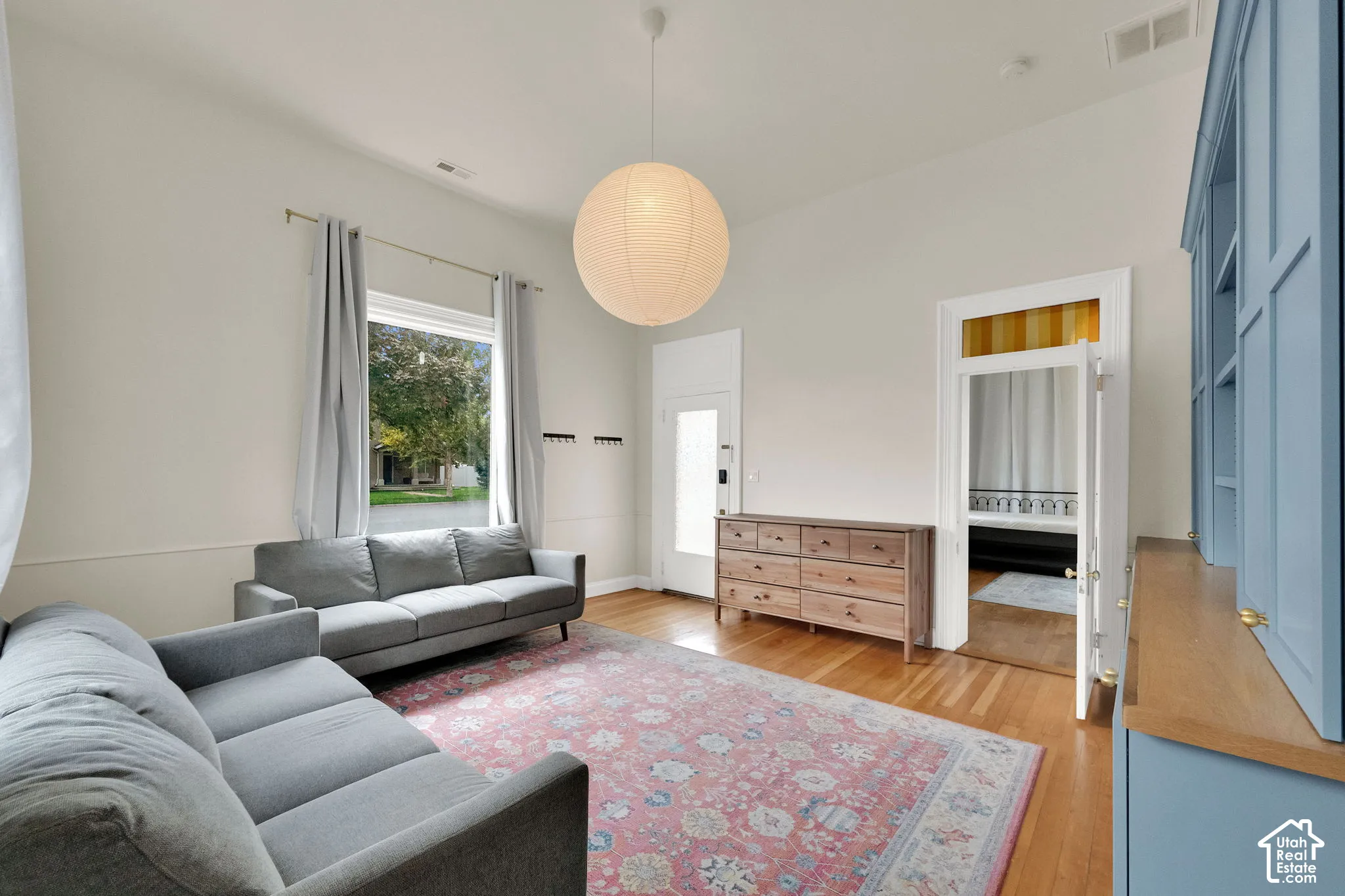 Hardwood flooring, vaulted ceiling, large window with natural light, built-in shelving, and a large hanging light fixture