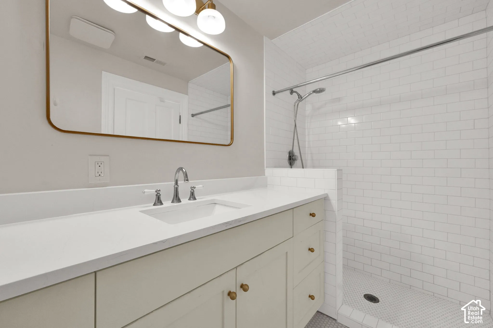 White subway tile shower enclosure with a mosaic tile floor, an integrated shower system, and a half-wall partition