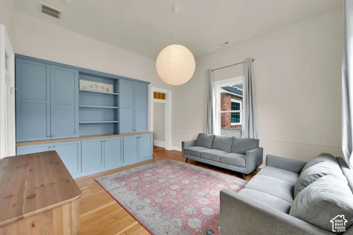 Built-in cabinetry with open shelving, wood-finish flooring, high ceilings, and a large window with natural light